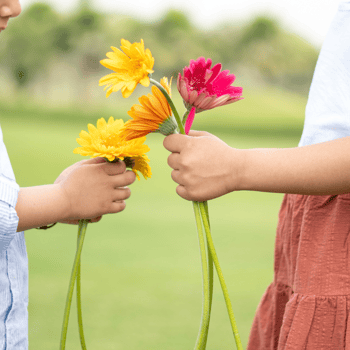 Two kids handing each other flowers.