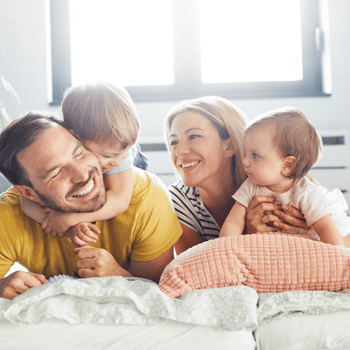 A family lying in bed together.