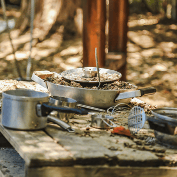 Pots and pans and kitchen utensils filled with mud for a mud kitchen.