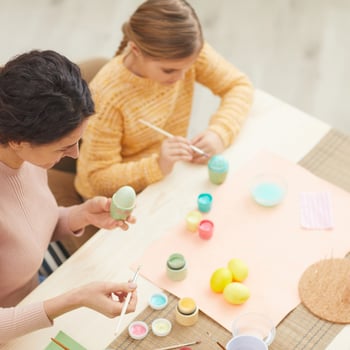 A girl and her mom painting Easter eggs.