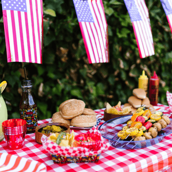 An outdoor bbq set up with kabobs, hamburger buns, hotdog buns, and condiments.