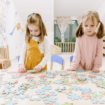 Little girls doing a puzzle together.