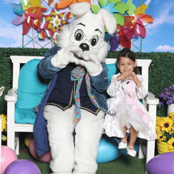 A little girl with the Easter Bunny making heart signs with their hands.