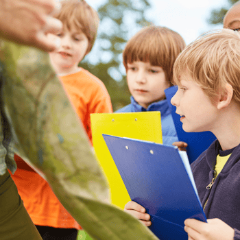 A group of kids looking at a map during a scavenger hunt.