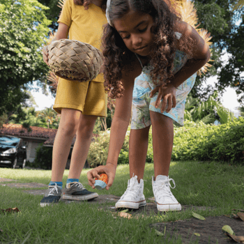 A girl picking up a toy during a treasure hunt.