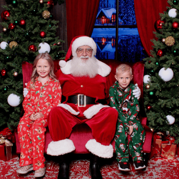 A little boy and girl in Christmas PJ's sitting with Santa.