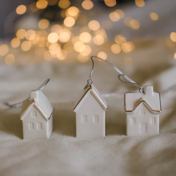 A white Christmas village set with fairy lights in the back.