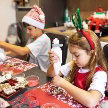 A little boy and girl icing Christmas cookies.