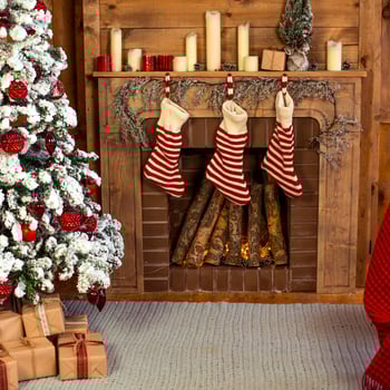 A Christmas tree with presents next to a fireplace with stockings hung.