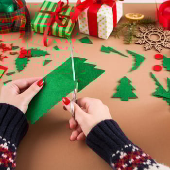 A lady cutting a felt Christmas tree piece.