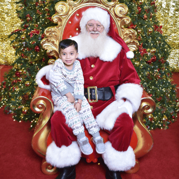 Little boy in Pj's sitting with Santa