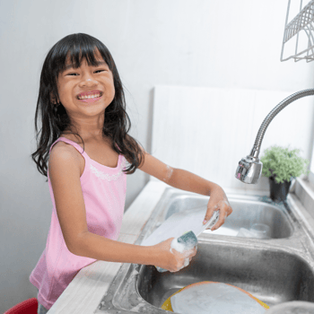 A little girl washing dishes.