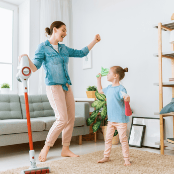 A little girl and her mom dancing while cleaning.