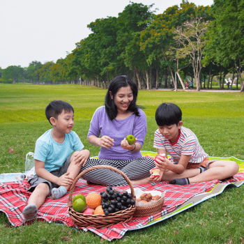 A mom and her two boys sharing a picnic in a park.