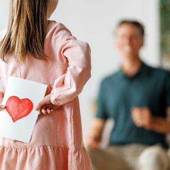 A little girl holding a handmade card for her dad.