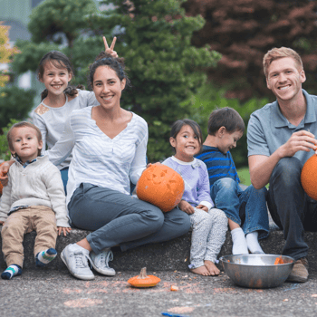 A family posing for a picture while carving pumpkins.