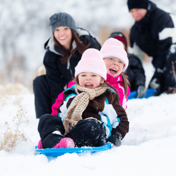 A family sledding in the snow.