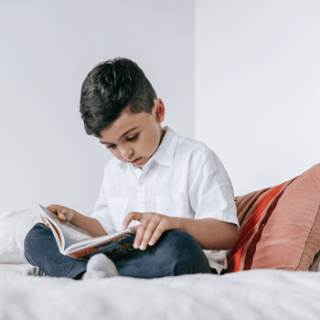A little boy reading in bed.