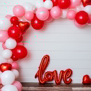 A red, white, and pink balloon arch with a "love" balloon.