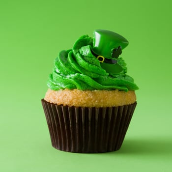 A green icing cupcake with a leprechaun hat