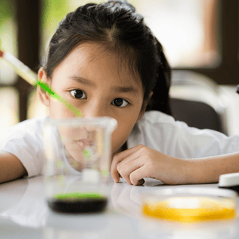 A girl using a pipette and beaker for a science experiment.