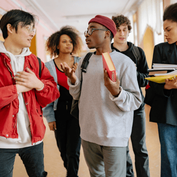 A group of teens talking in a school hallway.