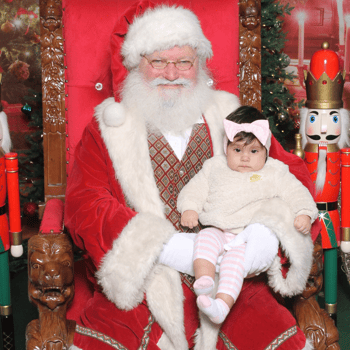 A baby girl sitting with Santa Claus.