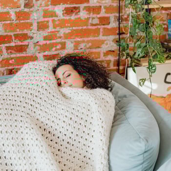 A mom resting in a comfy spot under a blanket.