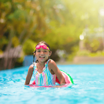 A little girl laughing in a pool floaty ring.
