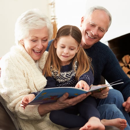 Grandparents reading a book with their granddaughter.