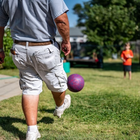 Dad and son kicking a kick ball