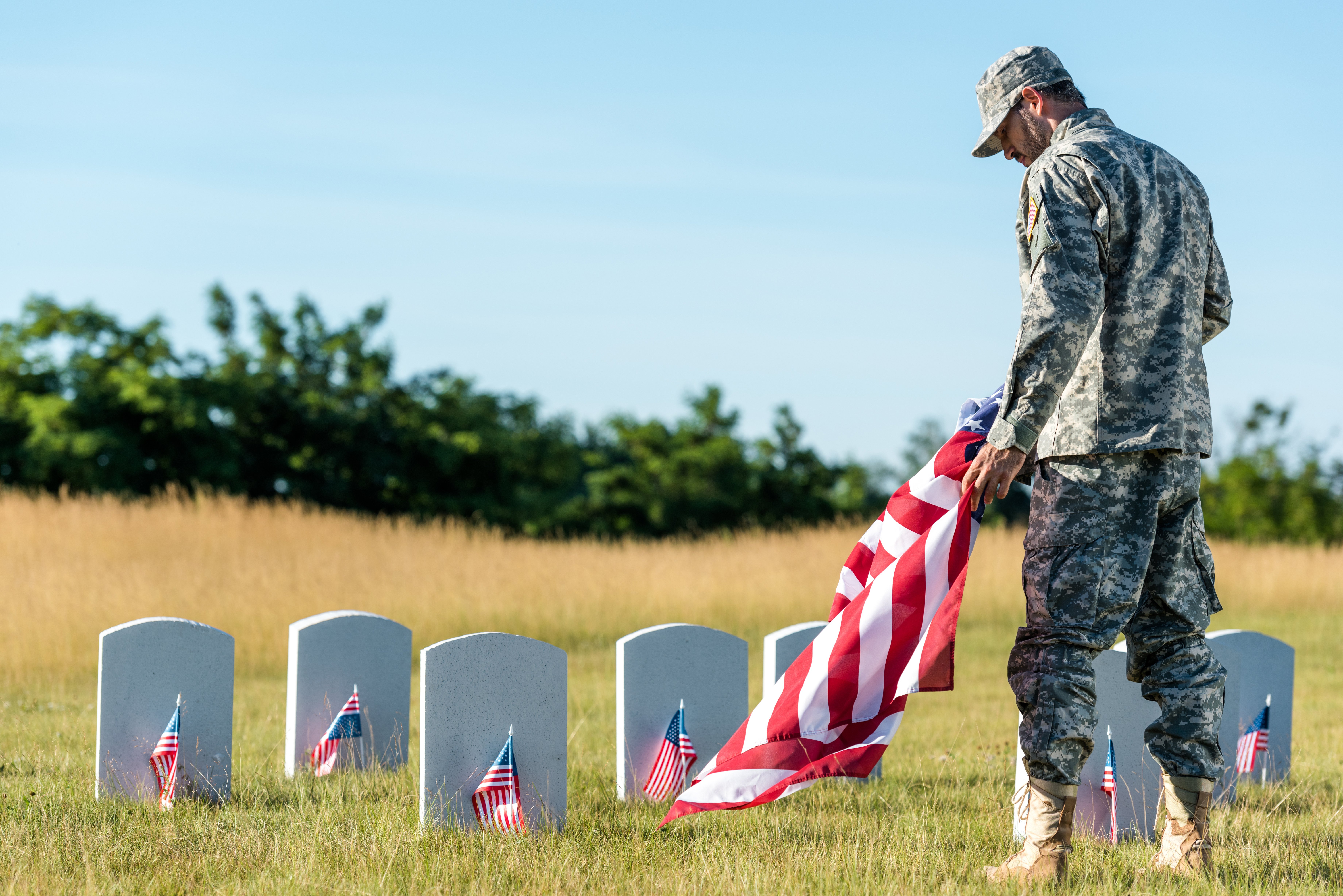 soldier holding flag in front of gravestone cemetery flags