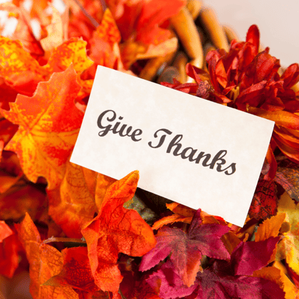 Card that says Give Thanks surrounded by colored leaves.