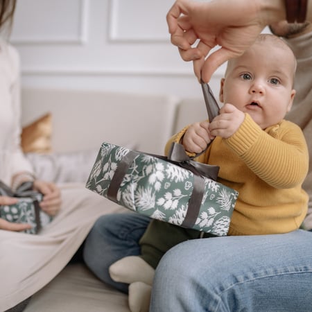 A baby opening a gift with their dad.