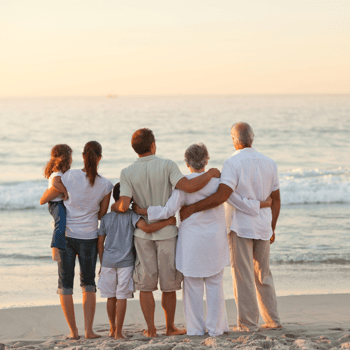 A family watching the sunset together on the beach.
