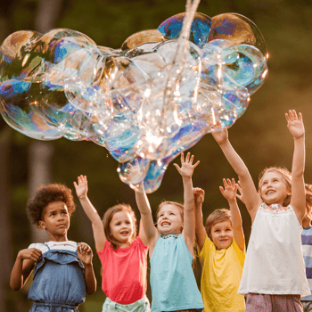 Kids playing with a giant bubble in the air.