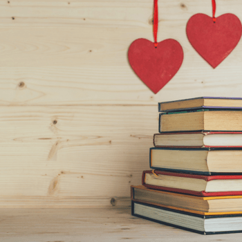 A stack of books with two red hearts hanging above it.