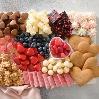 A valentine charcuterie board with heart shaped candy, cookies and chocolate.
