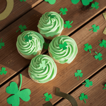 Green cupcakes with clovers around them.