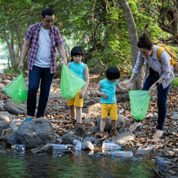 A family cleaning up litter together along a river bed.
