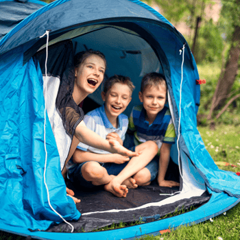 Kids inside of a tent outside.