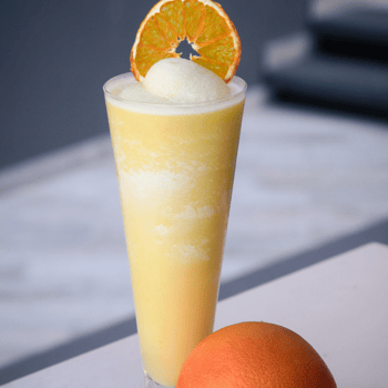 Orange creamsicle float in a glass with an orange next to it.