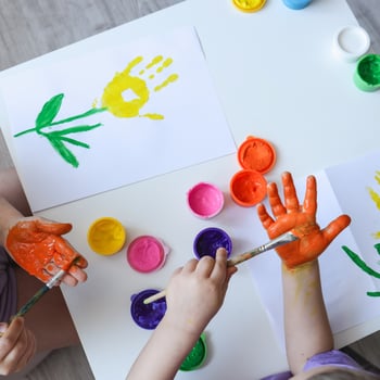 Kids painting handprint flowers.