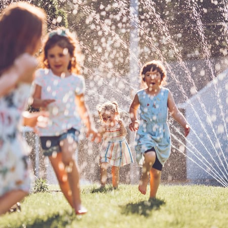 Kids running through a sprinkler