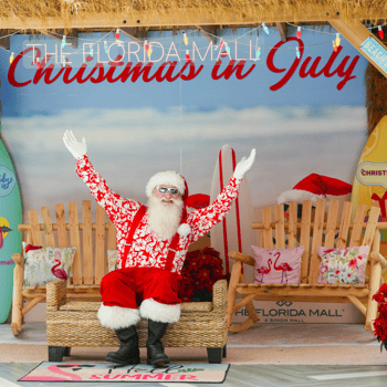 Santa sitting in a chair surrounded by surf boards.