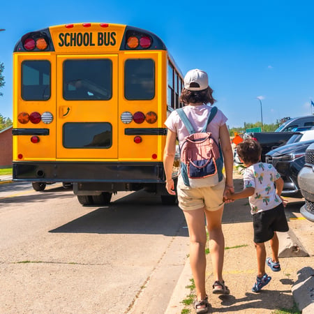Two kids walking up to a school bus.