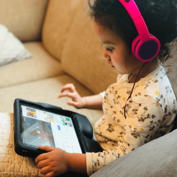 A little girl watching a tablet with headphones on.