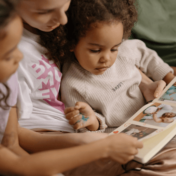 A mom and her daughters looking at a photo book.