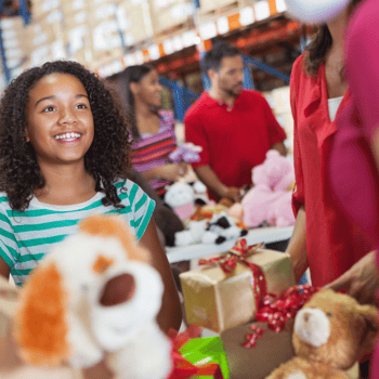 A little girl at a toy drive giving away toys.