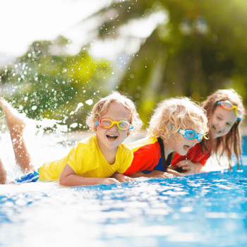 A group of kids splashing on the side of the pool.